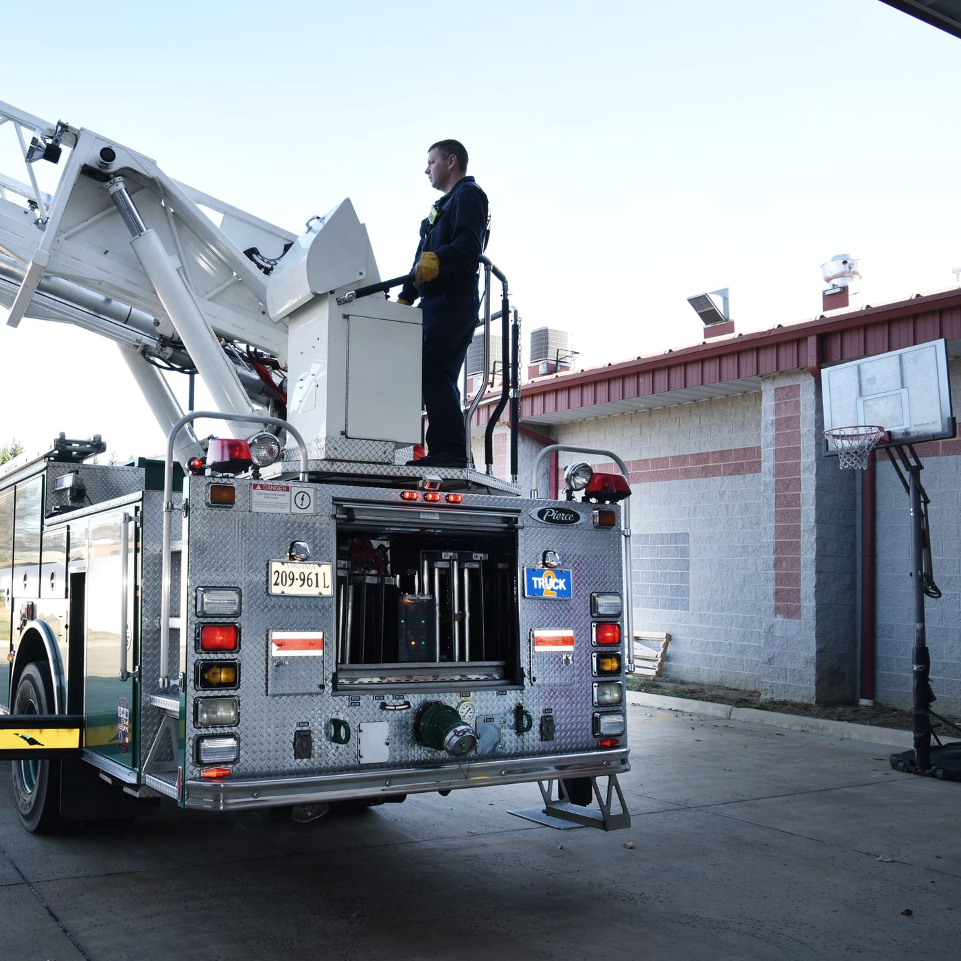 An aerial ladder truck with its ladder extended, a firefighter working at the turntable